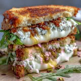 Goat Cheese Grilled Cheese with Honey & Chili Flakes resting on a plate with fresh thyme and pear slices.