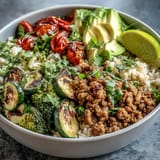 Hearty ground turkey bowl with roasted vegetables and brown rice, garnished with fresh cilantro and avocado slices.