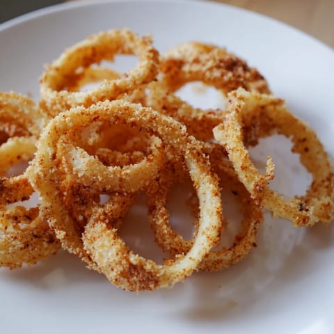 A close-up of freshly fried, golden brown onion rings, displaying their light, airy batter.