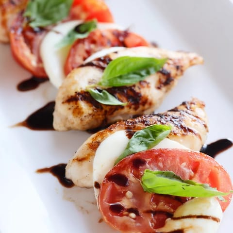 Golden-brown Caprese Chicken Skillet bubbling with melted mozzarella and fresh tomato slices, garnished with basil and a balsamic drizzle.