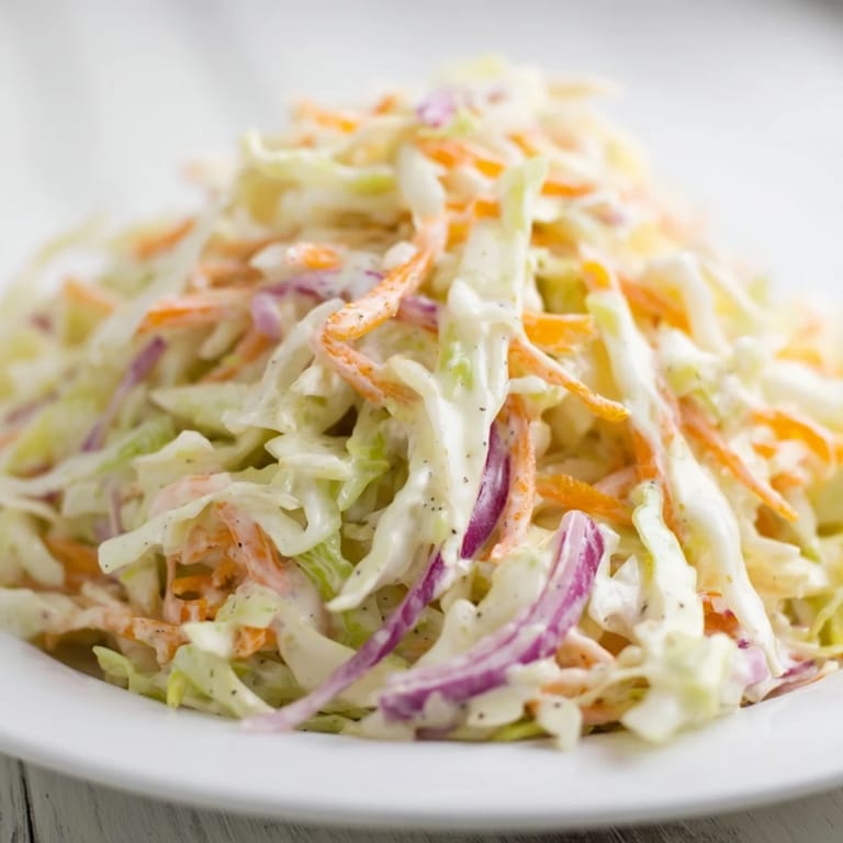 Cool and refreshing coleslaw, with crunchy vegetables coated in a tangy dressing, ideal as a side.