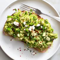 Golden toasted sourdough bread topped with creamy smashed pea and shredded chicken mixture, garnished with vibrant chili flakes and fresh mint.