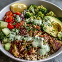Vibrant Rotisserie Chicken Bowl with fluffy quinoa, crisp cucumbers, and creamy avocado, drizzled with tangy tzatziki sauce.