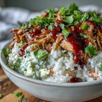 A close-up of a vibrant Pulled Pork Bowl with slow-cooked shredded meat, fluffy rice, crunchy coleslaw, and BBQ sauce drizzle.